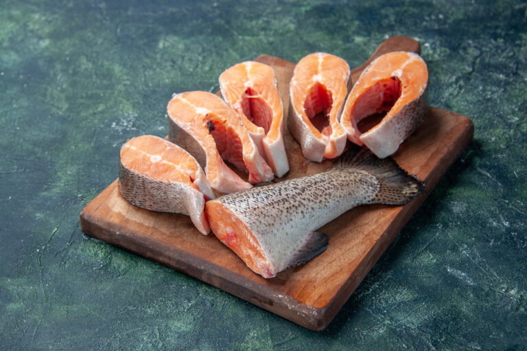 side-view-fresh-raw-fishes-brown-wooden-cutting-board-dark-mix-colors-table-with-free-space